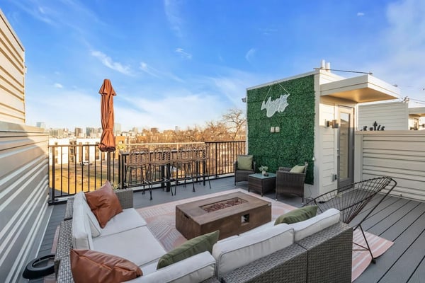 Rooftop terrace with seating area, fire pit, ivy-covered structure, and city skyline view